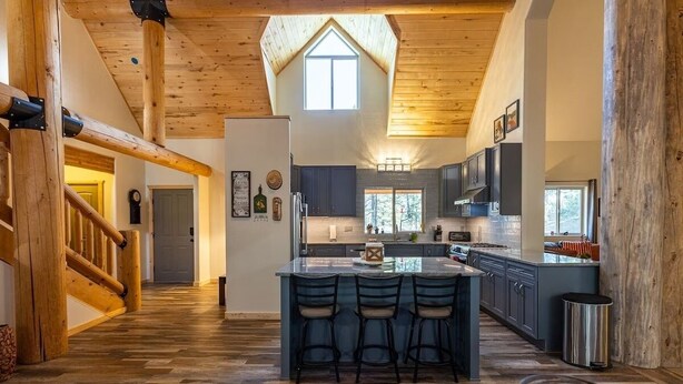 A spacious kitchen with a central island, wooden flooring, and a high ceiling with exposed beams. - Secluded, Spacious, Close to Town, Large Lot, Great Family Home, Hot Tub (Pagosa Springs)