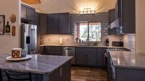 A modern kitchen with dark cabinets, stainless steel appliances, and a large island. - Secluded, Spacious, Close to Town, Large Lot, Great Family Home, Hot Tub (Pagosa Springs)