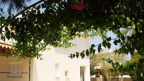 A white building with a tiled roof, a small garden, and a metal fence. - Villa Nektaria Green Bay DPSV308 (Paralimni)