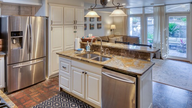A modern kitchen with stainless steel appliances, a granite countertop, and a large island with a sink. - The Sarah Elizabeth House on beautiful Jones St w/ Private Courtyard (Savannah)