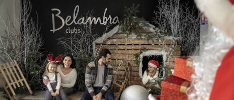 A family sitting on a bench with a wooden backdrop and a sign that reads "Belambra clubs".