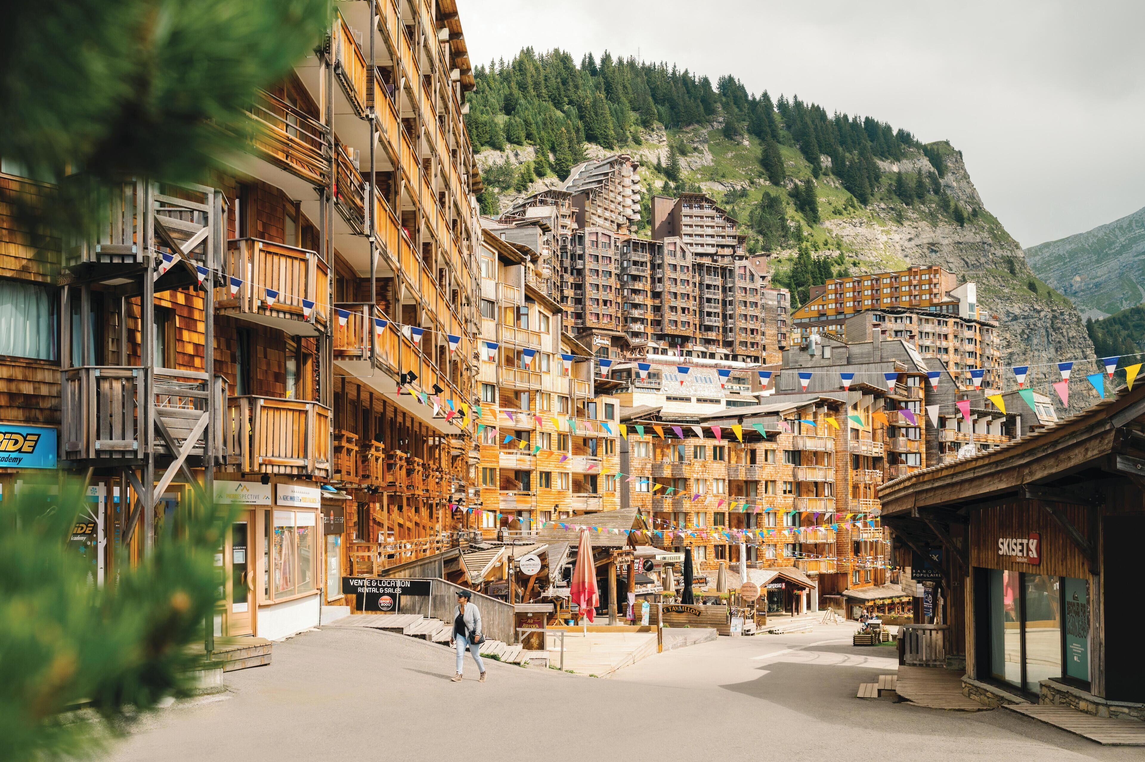 A mountain resort with multi-story buildings, balconies, and a central pedestrian area.