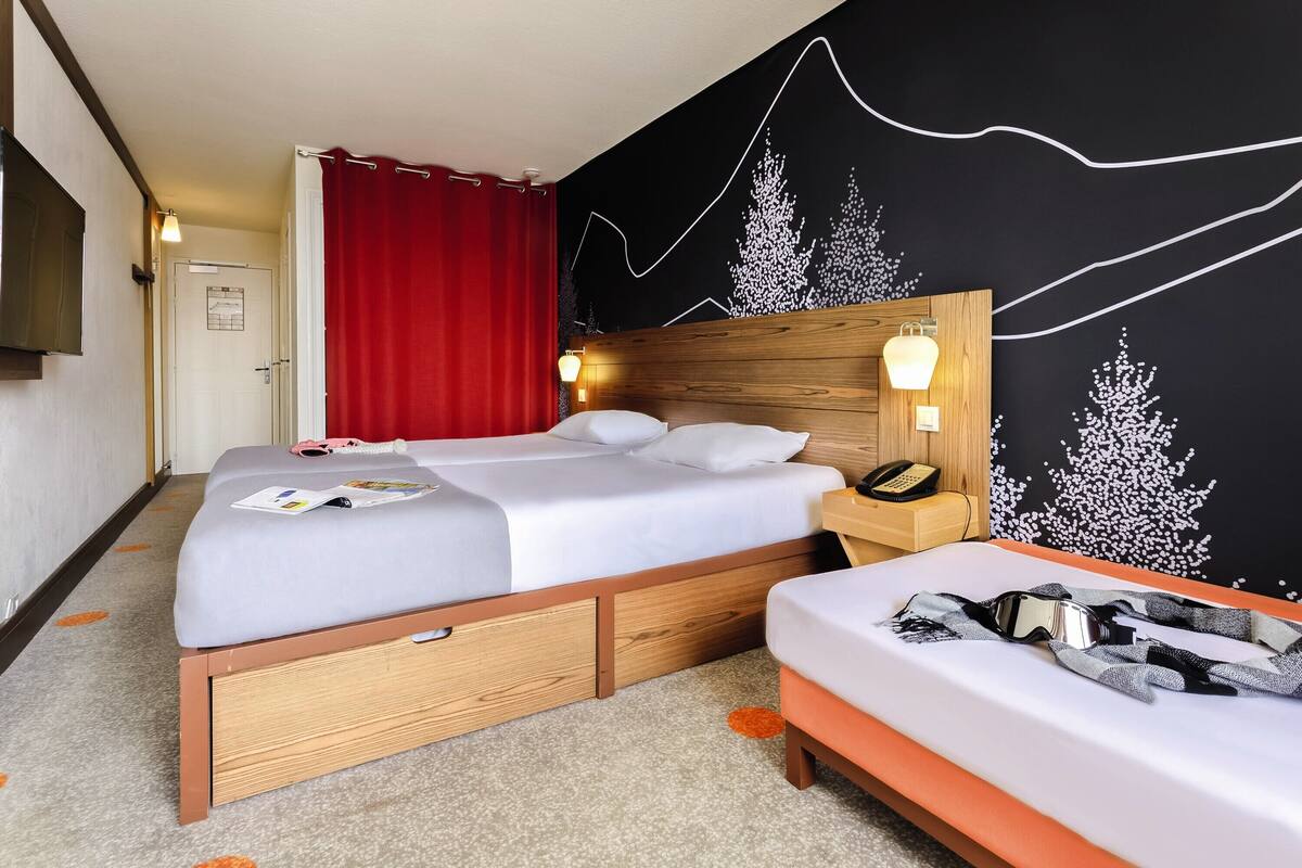 A bedroom with a bed, bedside table, and a wall-mounted phone.