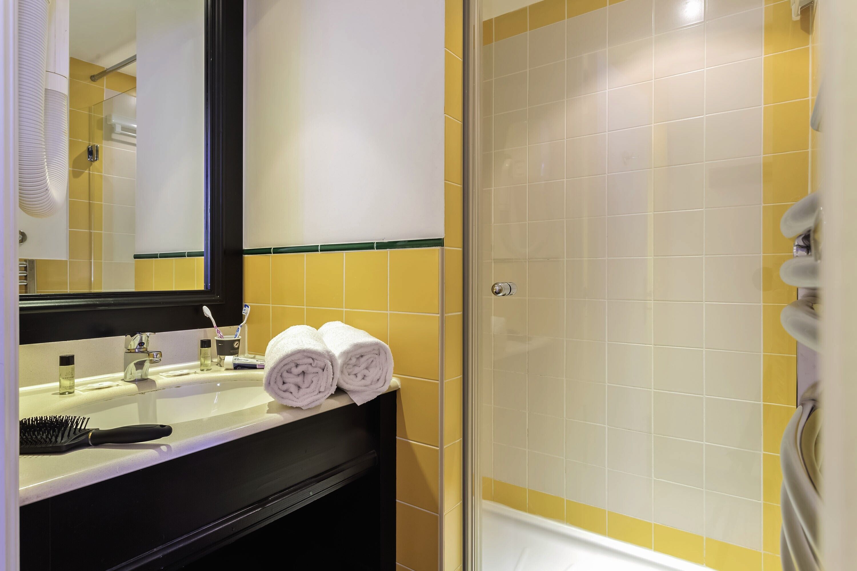 Une salle de bain avec un lavabo, un miroir et deux serviettes posées sur le comptoir.