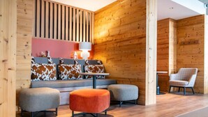 A modern interior with a wooden wall, a sofa with cowhide cushions, and two ottomans. - Belambra Clubs Avoriaz - Les Cimes du Soleil  (Morzine)