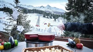 A table with a basket of food, a red pot, and a frying pan on a balcony overlooking a snowy mountain. - Belambra Clubs Arc 1800 - Hôtel Du Golf  (Bourg-Saint-Maurice)