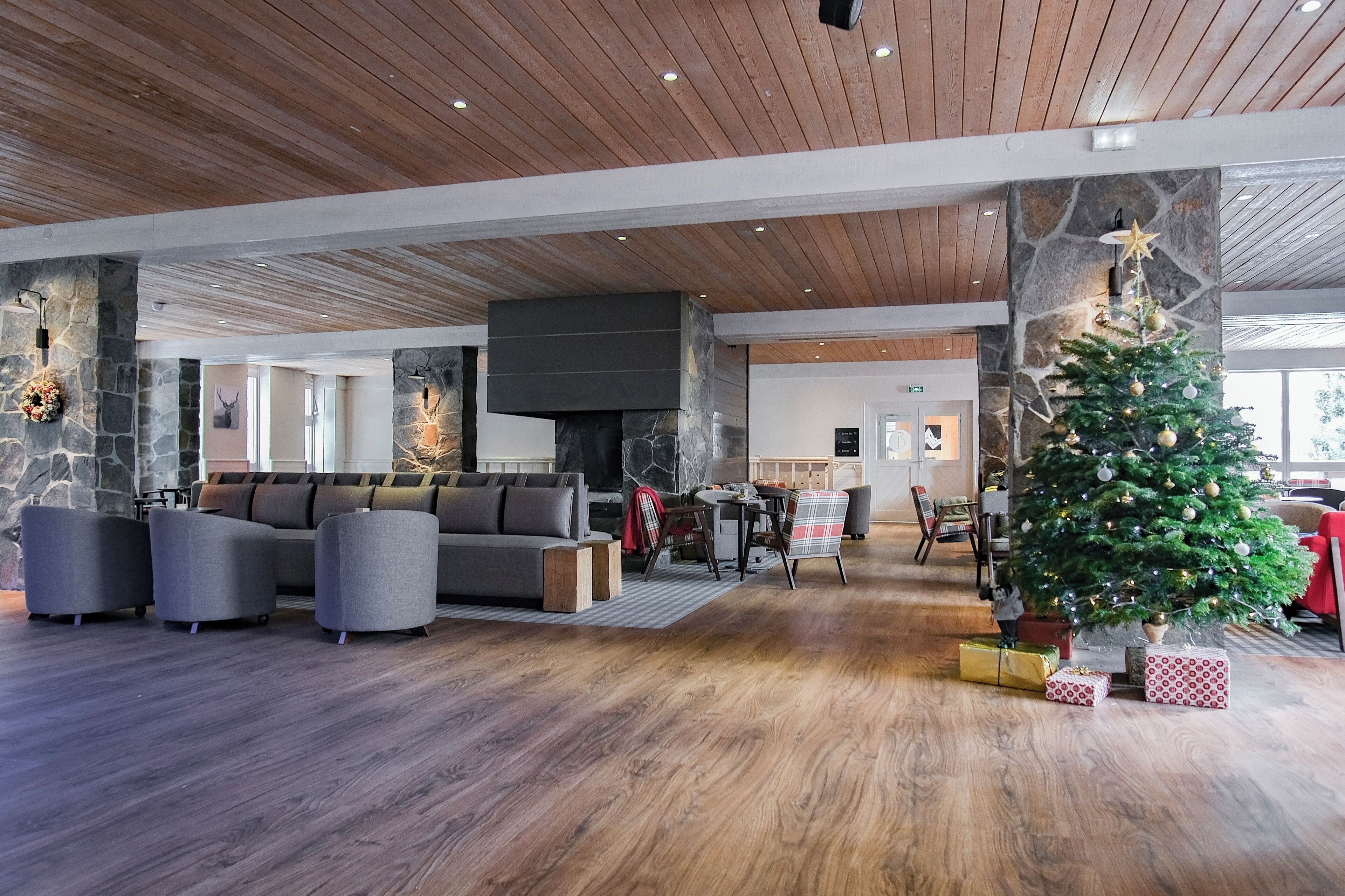A spacious living area with a stone fireplace, a large gray sofa, and a Christmas tree.