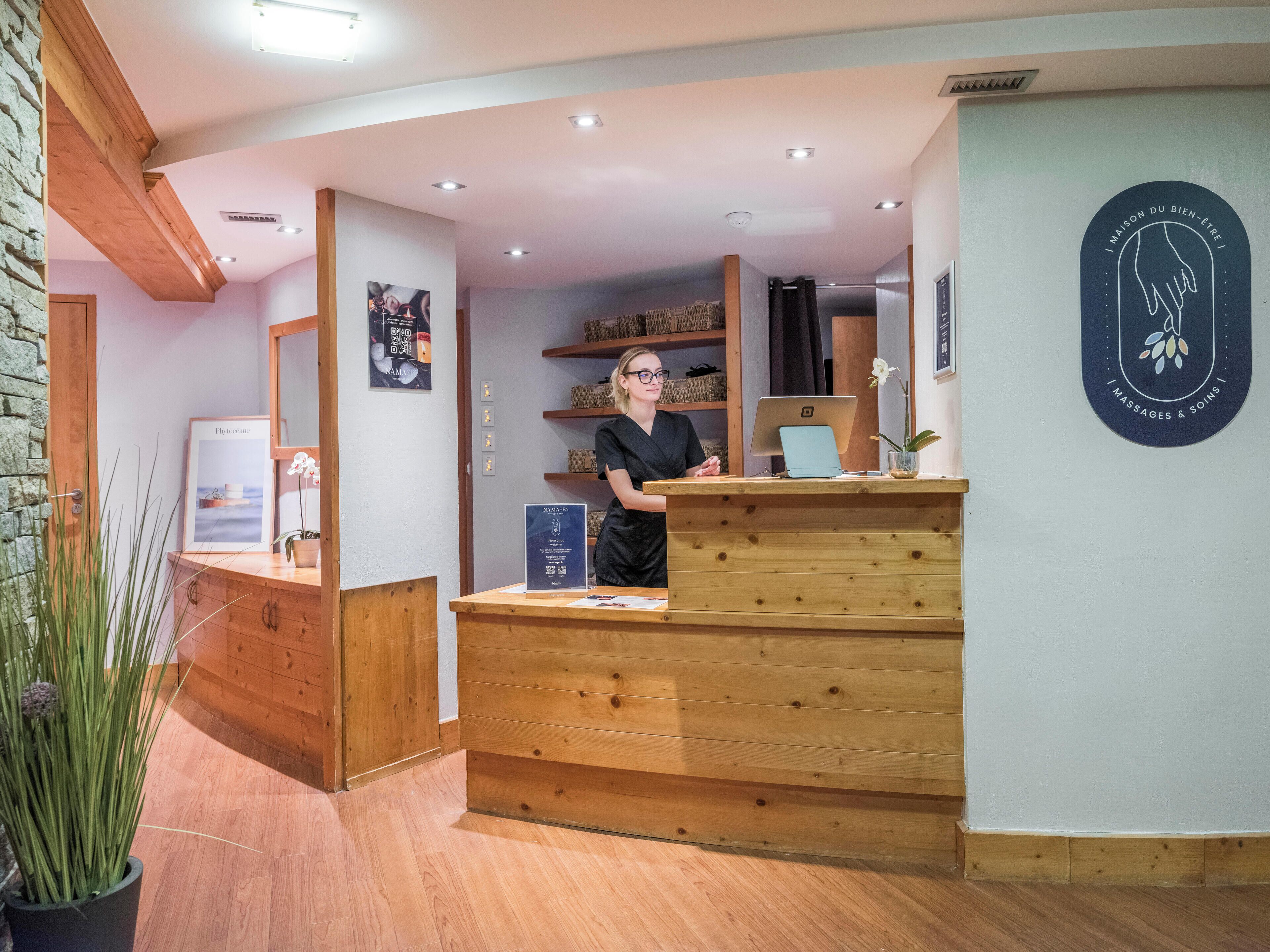 A reception desk with a wooden finish, a computer, and a framed certificate on the counter.