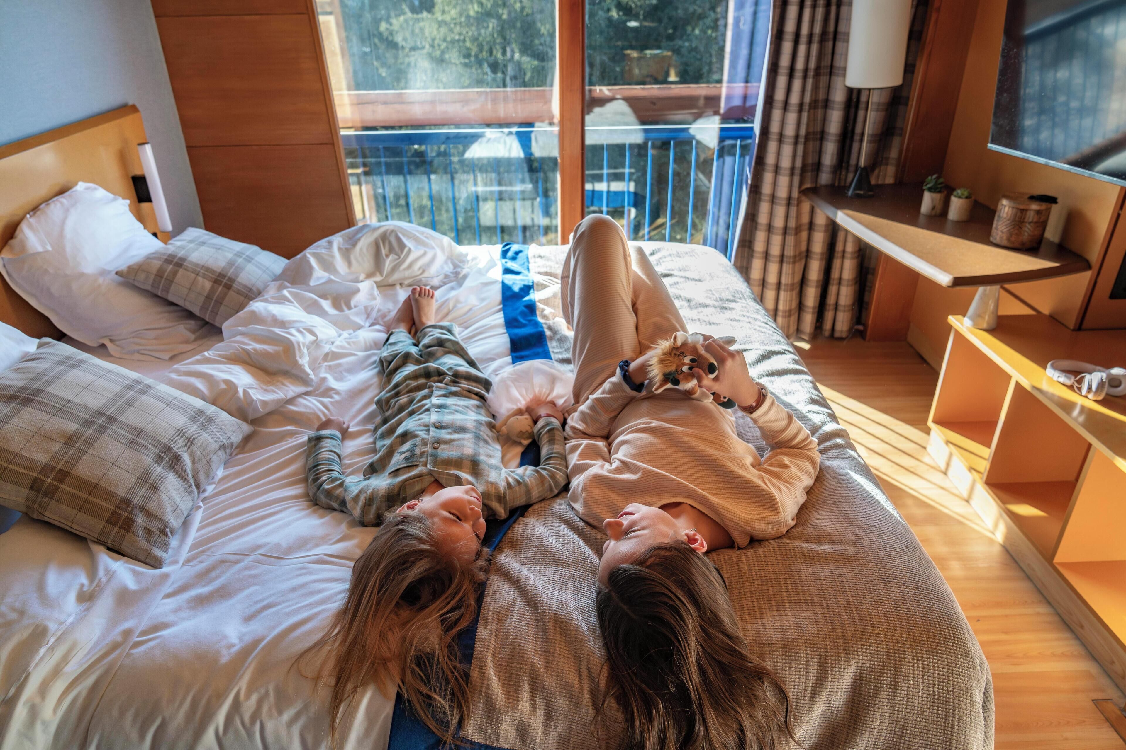 Un dormitorio con cama, cabecera de madera, ventana con vistas al exterior y una mesita de noche con lámpara.