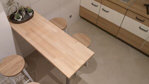 Una cocina con encimera de madera, dos taburetes y un armario con cajones.