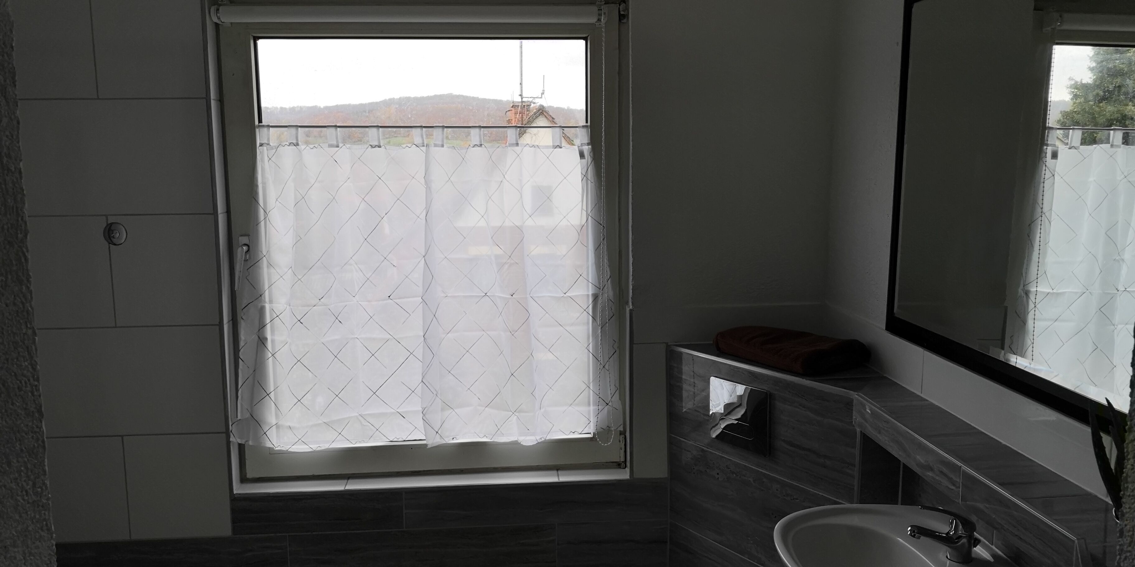 Un baño con un ventanal grande, un espejo y un lavabo.