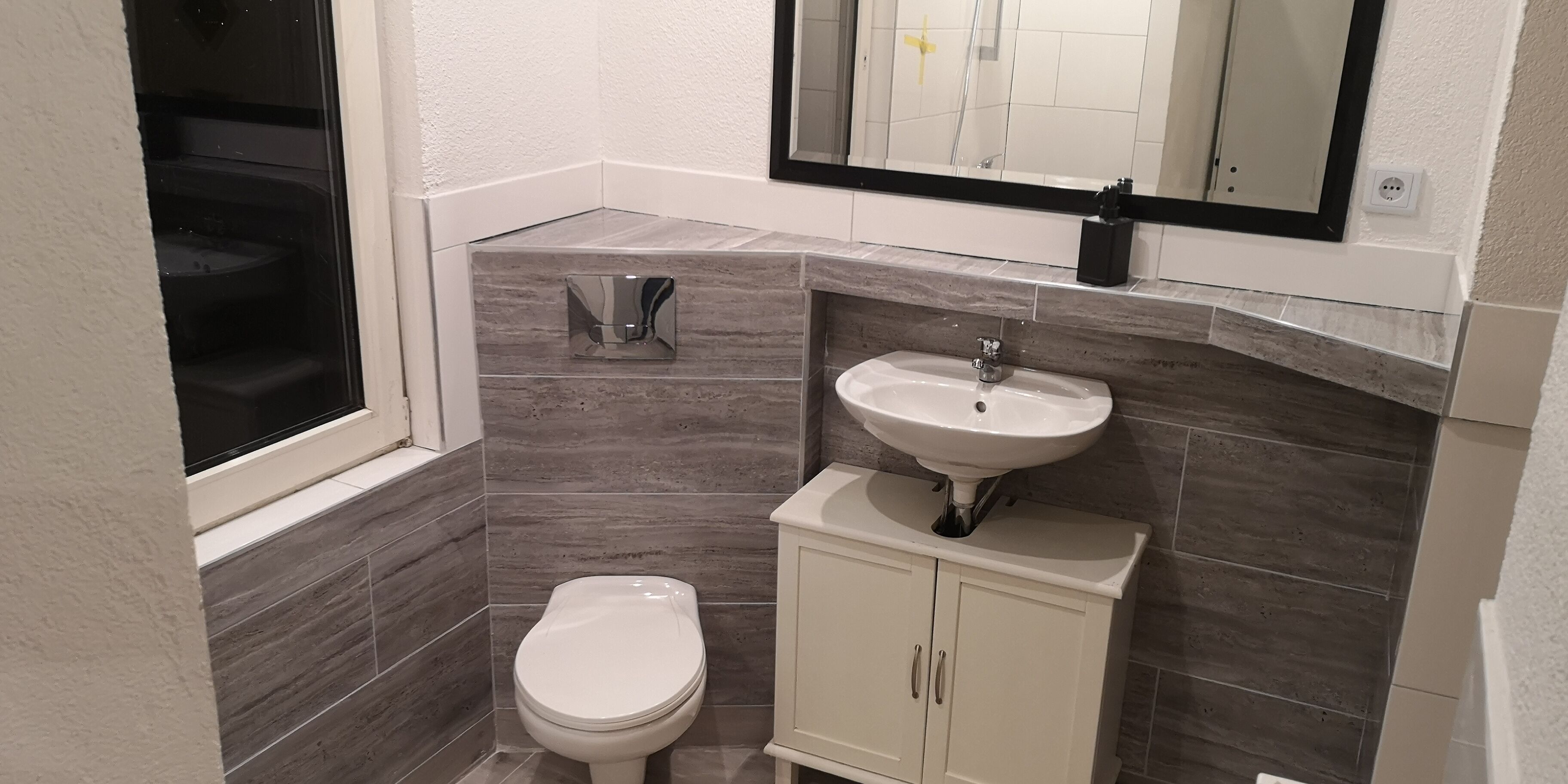Een badkamer met toilet, wastafel en spiegel.