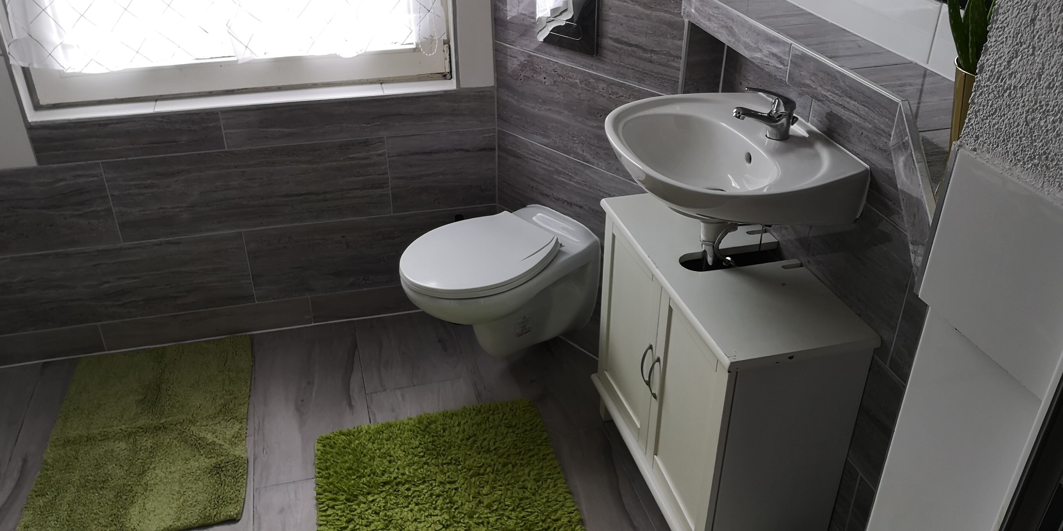 Un baño moderno con inodoro, lavabo y una alfombra verde.