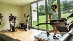 A gym with treadmills, stationary bikes, and a large window offering a view of the outdoors. - Belambra Clubs Résidence Rocamadour - Les Portes De Dordogne (Alvignac)