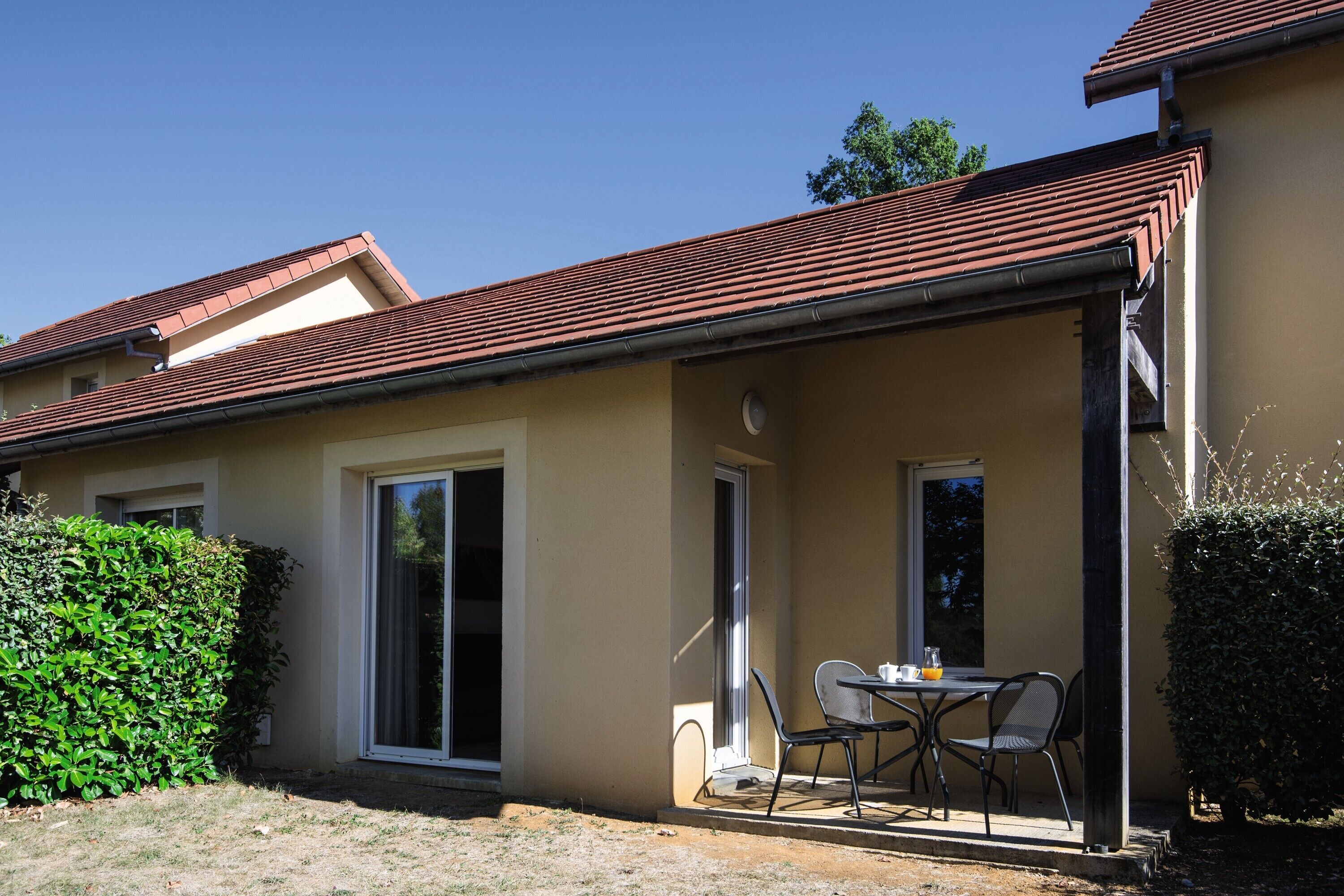 A house with a covered patio, a dining table, and chairs.