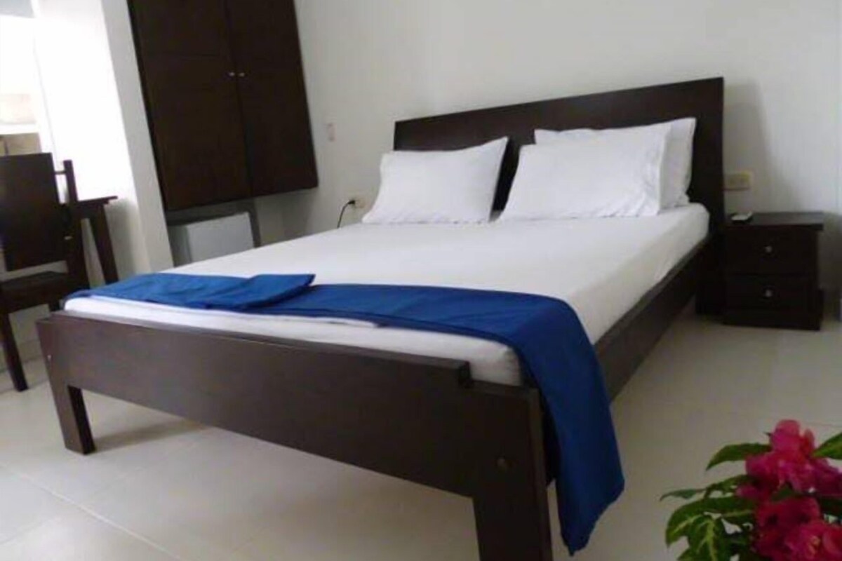 Ein Schlafzimmer mit Bett, Nachttisch, Kleiderschrank und Stuhl.