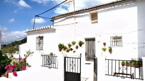 A white building with black railings, potted plants, and a clear sky. - The countryside of Cruzchiquita (Alpandeire)