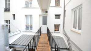 A narrow corridor with wooden flooring, metal railings, and white walls. - Lafayette Hotel (Paris)