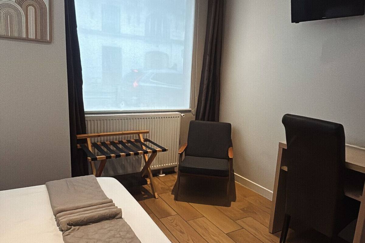 A hotel room with a bed, a desk, a chair, and a large window.