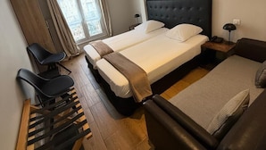 A hotel room with a large bed, a sofa, a desk with chairs, and a window with curtains. - Lafayette Hotel (Paris)