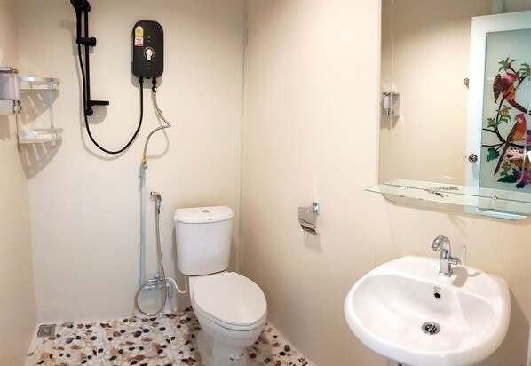 A bathroom with a toilet, a shower, and a sink.
