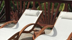 Dos sillones de madera con cojines blancos en un patio de piedra.