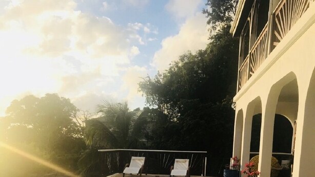Una piscina con sillas de descanso, rodeada de baldosas de piedra y plantas en macetas.