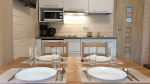 Comedor con mesa de madera dispuesta para cuatro, con platos, cubiertos y copas.