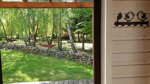 A wooden door with a black bird decoration and a view of a garden with a hammock and stone wall.