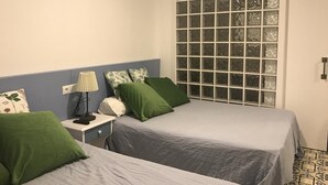 A room with two beds, a nightstand, a lamp, and a window with a grid pattern. - D2 Ducal Apartment with private pool (Gandia)