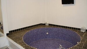 A room with a circular hot tub, a black flat-screen TV mounted on the wall, and decorative lanterns on the floor. - D2 Ducal Apartment with private pool (Gandia)