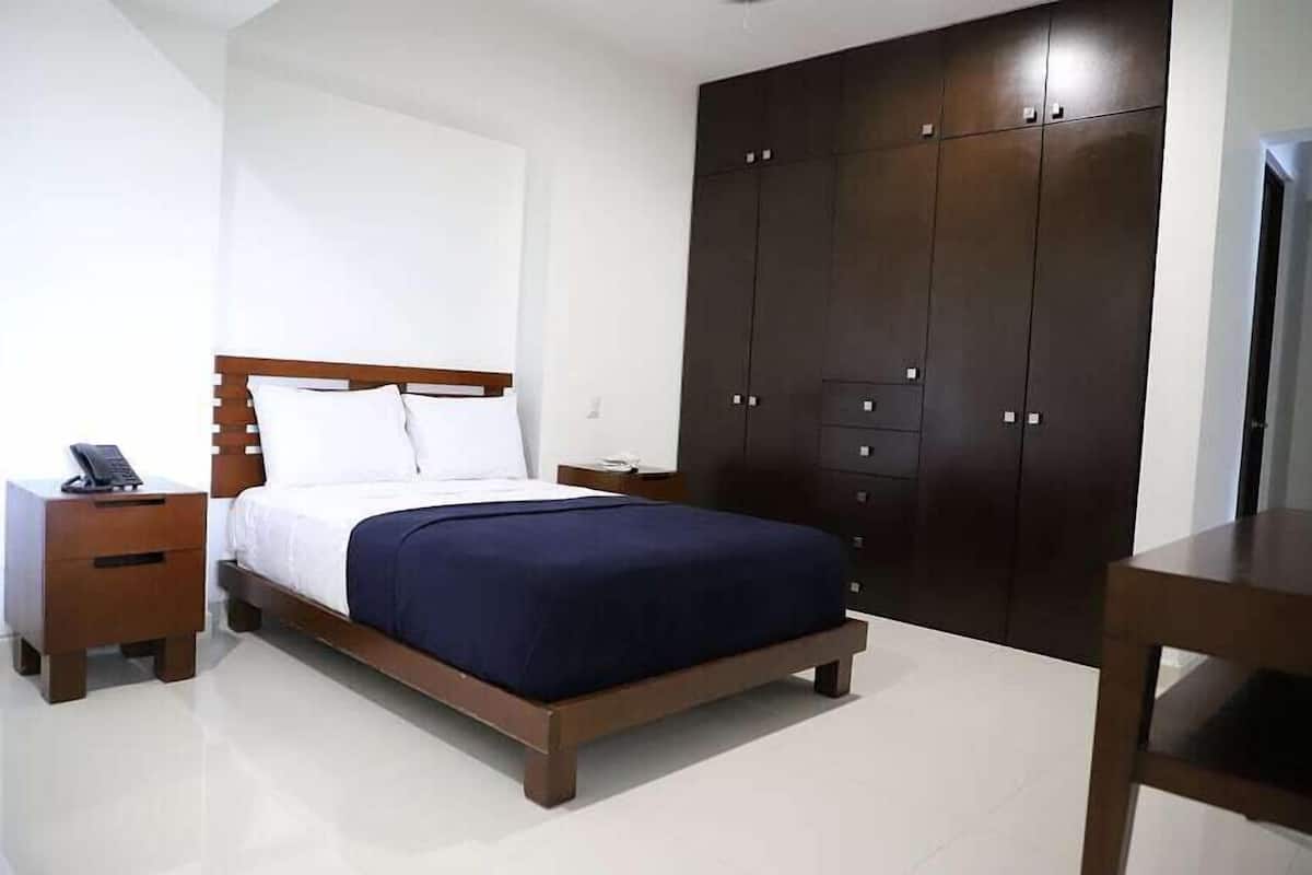 A bedroom with a wooden bed, a nightstand, a wardrobe, and a desk.