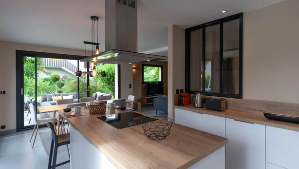 Una cocina moderna con encimera de madera, estufa integrada y un amplio ventanal con vistas a un jardín.