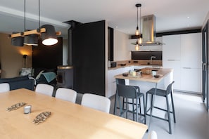 A modern kitchen with white cabinets, a wooden island, and black chairs. - Lake Annecy contemporary house with private pool - Wifi (Saint-Jorioz)