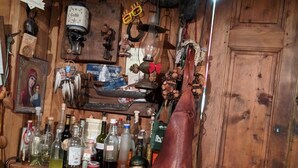 Een rustieke bar met houten wanden, verschillende flessen en een grote leren laars.