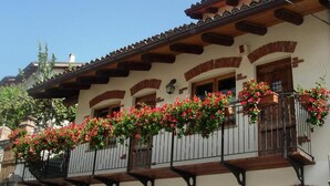 Een traditioneel gebouw met meerdere balkons, versierd met rode bloemen, houten balkons en een rustieke architectuur.