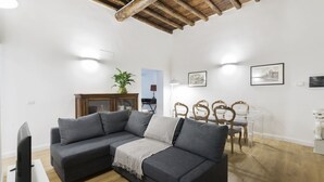 Un salon moderne avec un canapé d’angle gris, une table à manger en bois et des chaises.