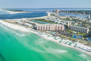 Eine Vogelperspektive eines Küstenresorts mit Strandhäusern, einer Marina und einer Brücke im Hintergrund.