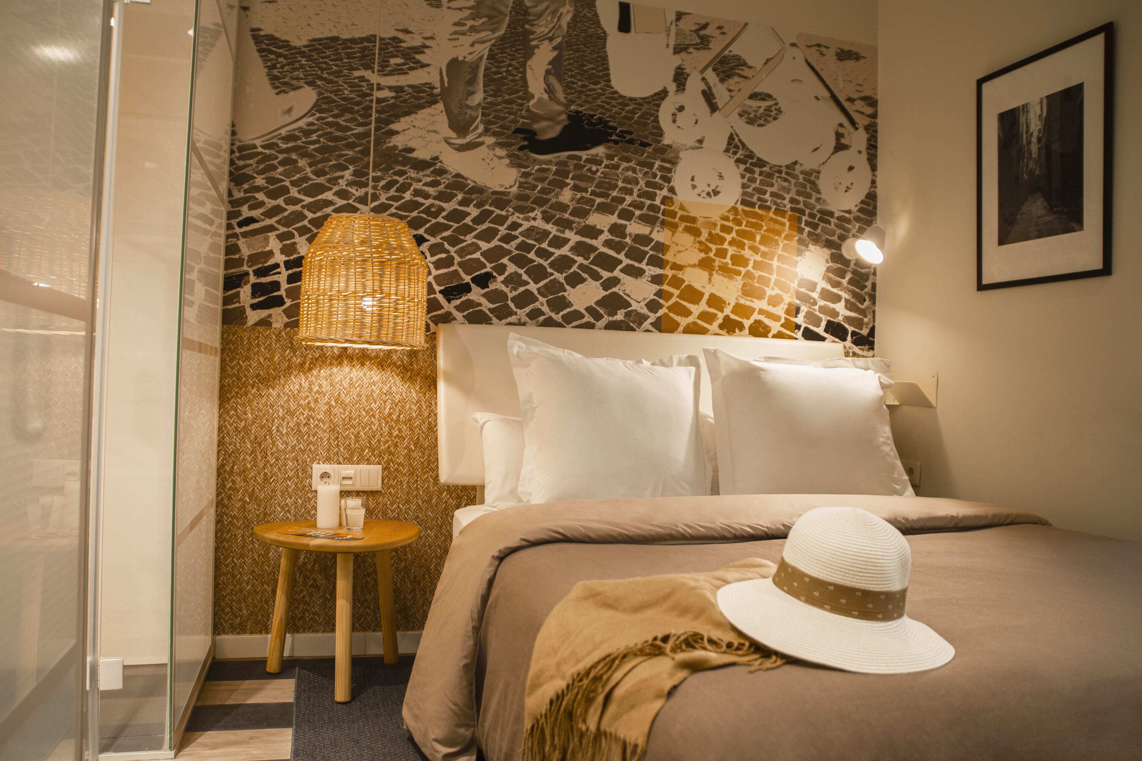 Une chambre à coucher comprenant un lit, une table de chevet, une lampe et un mur orné d’un motif en mosaïque.