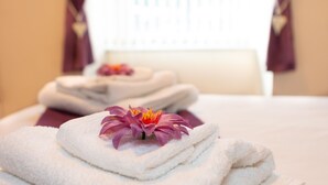 Un ensemble de serviettes soigneusement disposées sur un lit, avec une seule fleur posée sur le dessus.