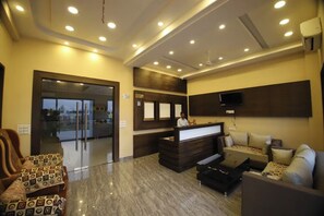 A hotel lobby with a reception desk, seating area, and a large window. - Virat Resorts, Sariska (Viratnagar)