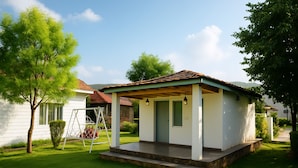 A small, single-story house with a covered porch, a swing set, and a well-maintained lawn. - Virat Resorts, Sariska (Viratnagar)