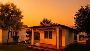 A small, single-story house with a porch and a swing set in the yard. - Virat Resorts, Sariska (Viratnagar)