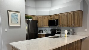 A kitchen with wooden cabinets, a black refrigerator, a stainless steel sink, and a microwave. - Park City in the summer. Stay in completely remodeled condo close to Main Street (Park City)