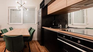 Enjoy meals at the dining table with four chairs, featuring a modern kitchen with a refrigerator, sink, and oven.