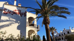 Un edificio con un letrero que dice "Siesta Hotel" y una palmera en primer plano.