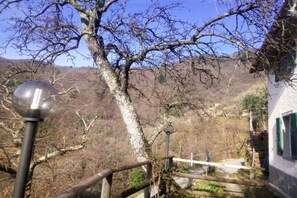 On peut admirer un paysage de montagne dégagé, avec une clôture en bois et un bâtiment blanc aux volets verts.