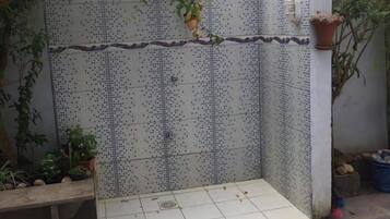 Pared de azulejos con un banco y plantas en macetas.