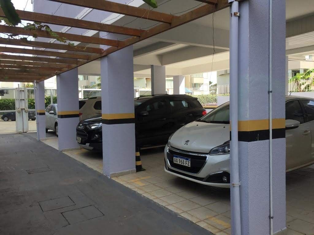 A covered parking area with multiple cars parked under a wooden pergola.