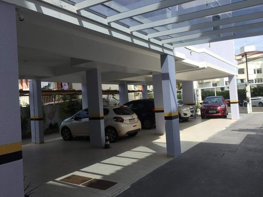 Un área de estacionamiento techada con varios coches aparcados bajo una estructura de techo transparente.